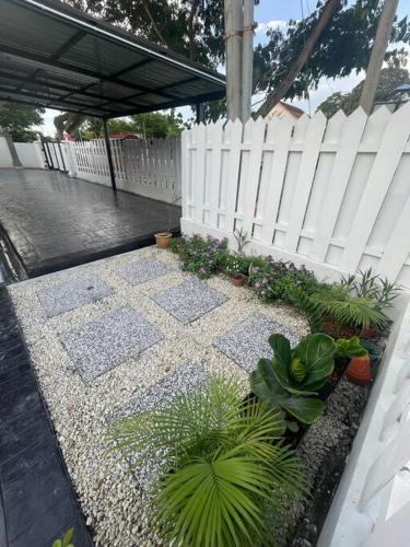 a white fence and some plants and some plants at Rossini Homestay in Muar