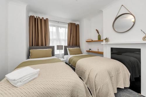 two beds in a room with a fireplace and a mirror at Wherstead Rd House By Homestyles Hosts Short Lets & Serviced Accommodation Suffolk With Free Parking in Ipswich