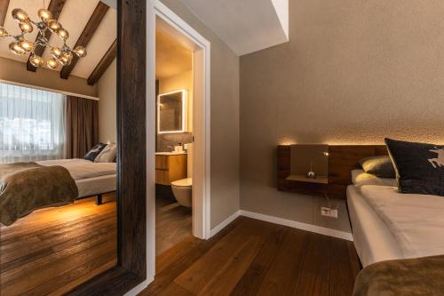 two beds in a room with a mirror and a bathroom at Elfi - luxury mountain bijou by Inspiringplaces Zermatt in Zermatt