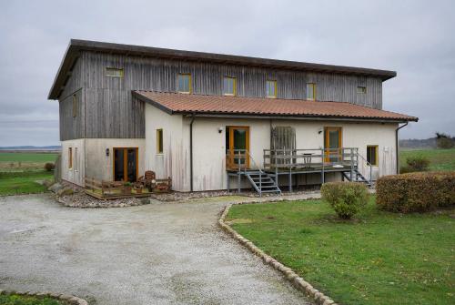 a large barn with a porch on a field at Ferienhaus Poggenkrug Halbsguth in Wolgast