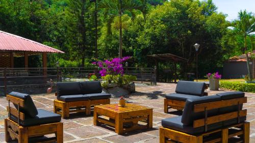 a patio with chairs and tables and purple flowers at Hotel Campestre Santa Catalina in San Gil