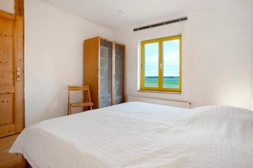 a white bedroom with a bed and a window at Ferienhaus Poggenkrug Halbsguth in Wolgast