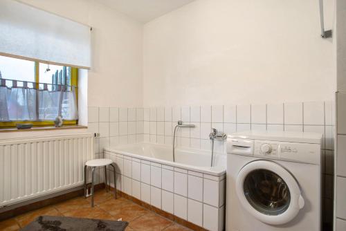 a white bathroom with a washing machine and a tub at Ferienhaus Poggenkrug Halbsguth in Wolgast