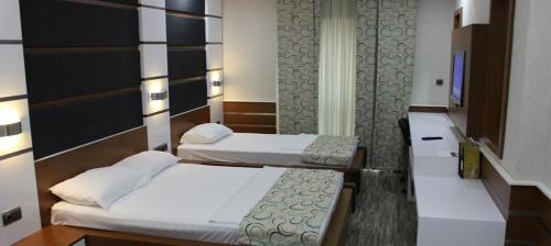 a room with two beds and a tv in it at Şehri Saray Otel in Seyhan