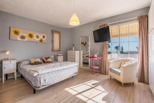 a bedroom with a bed and a chair and a television at Apartamentos Villa Martinez in Salobreña