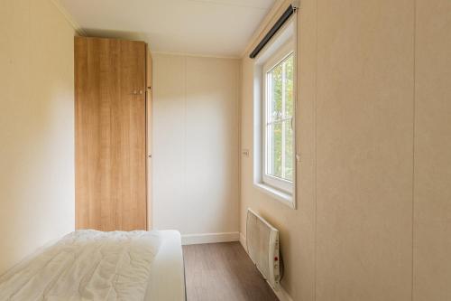 a bedroom with a bed and a window at Klein Finland - Chalet 6persoons in Wagenborgen