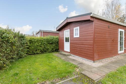 a small red shed with a grass yard at Klein Finland - Chalet 6persoons in Wagenborgen