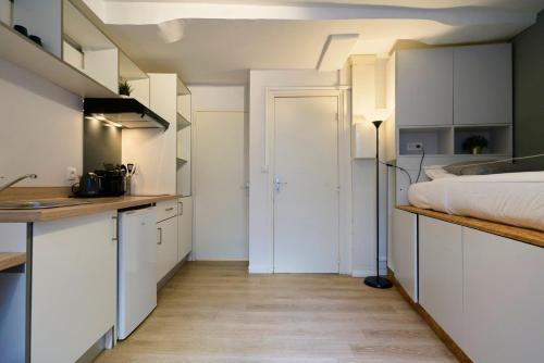 une cuisine avec des armoires blanches et un lit dans une chambre dans l'établissement Fully-equipped studio next to Lille Flandres, à Lille