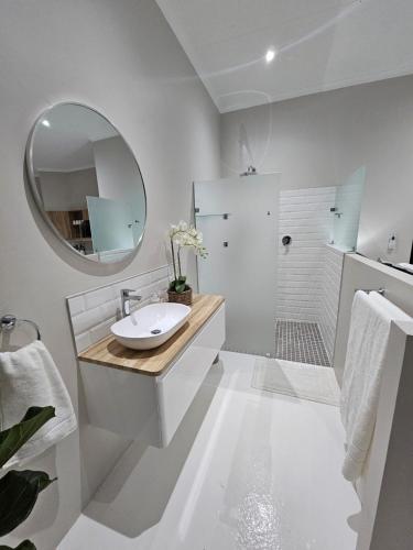 a white bathroom with a sink and a mirror at Levinia Cottage in Pretoria
