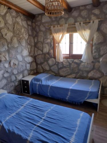 twee bedden in een kamer met een stenen muur bij Cabaña de piedra Los Crespines in San Antonio de Arredondo