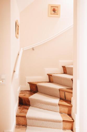 a stairway with white walls and wooden stairs at Hiidhüüs Wenningstedt unter Reet mit Sauna in Wenningstedt