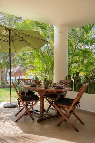 a wooden table and chairs with an umbrella at CHAC at Chac Hal Al Puerto Aventuras in Puerto Aventuras