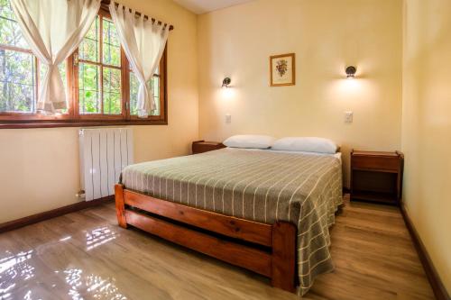 a bedroom with a bed and two windows at Hotel Turismo in San Martín de los Andes