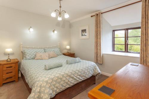 a bedroom with a bed and a table and a window at Hedgehog Cottage Wheddon Cross in Wheddon Cross