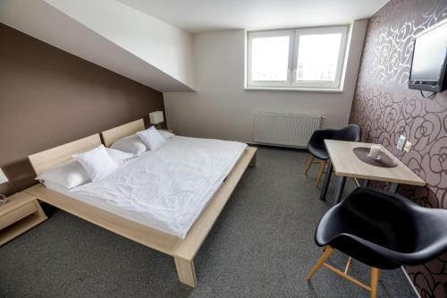 a bedroom with a bed and a table and chairs at Hotel Lion in Modřice