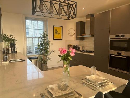 a kitchen with a table with a vase of flowers on it at Georgian Townhouse on the beach in Worthing