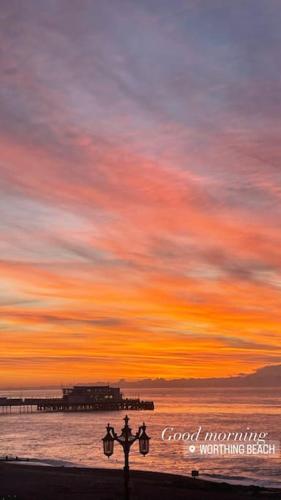 a sunset over the ocean with a street light at Georgian Townhouse on the beach in Worthing
