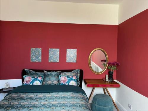 a bedroom with red walls and a bed with a mirror at Georgian Townhouse on the beach in Worthing