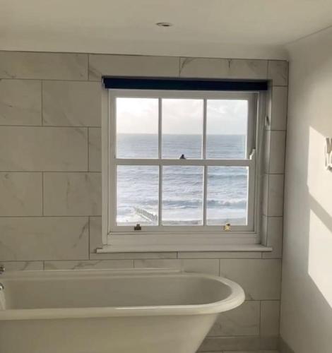 a bath tub in a bathroom with a window at Georgian Townhouse on the beach in Worthing