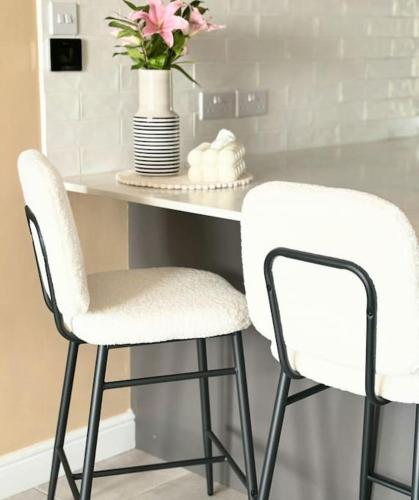 two white chairs and a table with a vase of flowers at Georgian Townhouse on the beach in Worthing