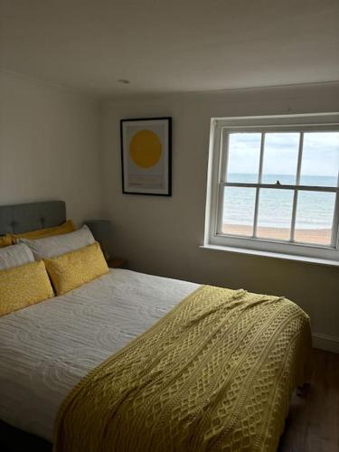 a bedroom with a bed with a yellow comforter and a window at Georgian Townhouse on the beach in Worthing