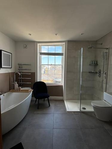 a bathroom with a tub and a shower and a chair at Georgian Townhouse on the beach in Worthing