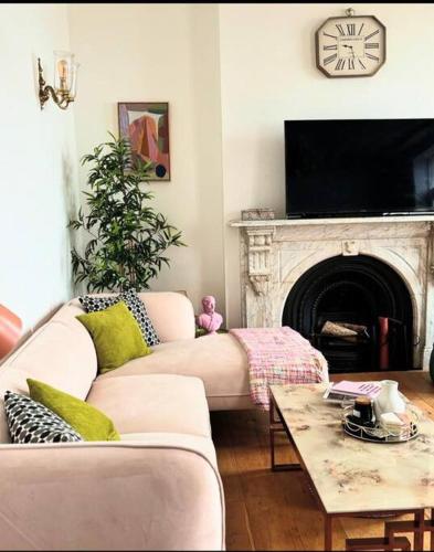 a living room with a couch and a fireplace with a clock at Georgian Townhouse on the beach in Worthing