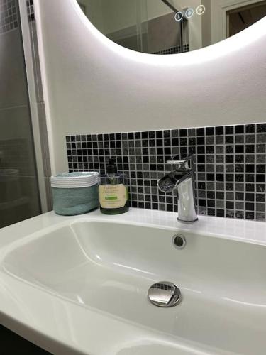 - un lavabo blanc dans la salle de bains avec un miroir et un lavabo dans l'établissement Maison de village, à Fourques