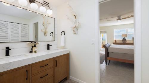 a bathroom with a sink and a mirror and a bed at Whispering Palms Sea Gulls 210 in Key Largo