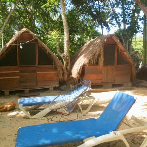 a couple of chairs and a house on the beach at Cabañitas y Dorms in Bacalar