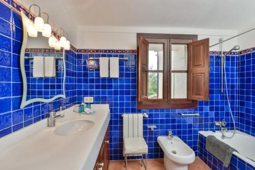 La salle de bains est pourvue de carrelage bleu, d'un lavabo et de toilettes. dans l'établissement Doppelzimmer Gregal Es Llobets, à Llucmajor