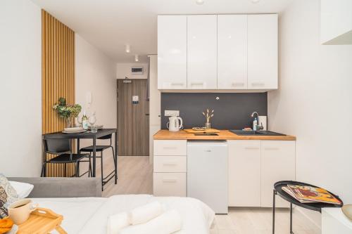 kuchnia i salon z białymi szafkami i stołem w obiekcie Prądnik Czerwony Studio - Balcony, City View - by Rentujemy w Krakowie