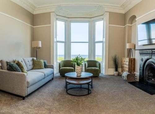a living room with a couch and two chairs and a table at King's Seafront Place in Cullercoats