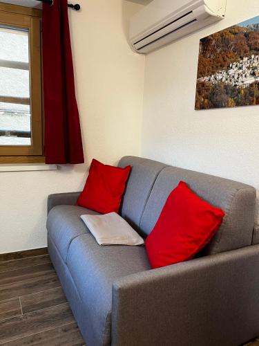 a gray couch with red pillows in a room at Chalet Letizia Mountain and Relax - Your Mountain Holiday in Premana