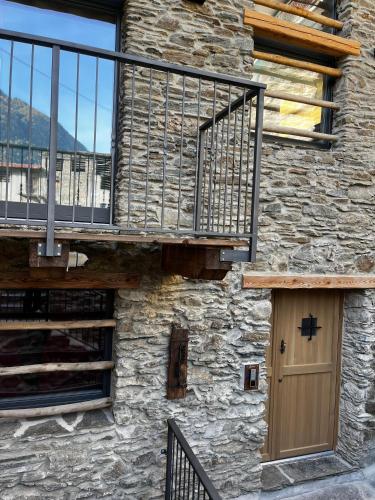 a stone building with a wooden door and a balcony at Chalet Letizia Mountain and Relax - Your Mountain Holiday in Premana