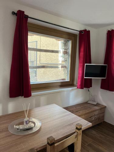 a room with a table and a window with red curtains at Chalet Letizia Mountain and Relax - Your Mountain Holiday in Premana