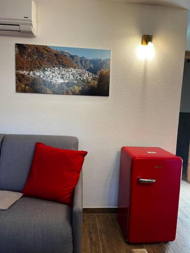 a room with a couch with a red pillow and a painting at Chalet Letizia Mountain and Relax - Your Mountain Holiday in Premana