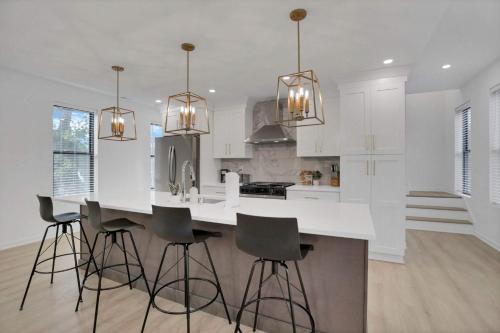 a kitchen with white cabinets and a island with bar stools at The Golden Hour - Luxury and Rooftop Hot Tub in Columbus