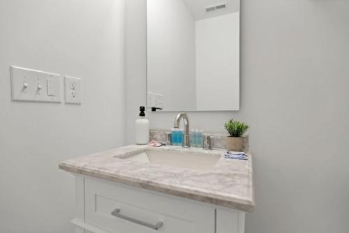 a white bathroom with a sink and a mirror at The Golden Hour - Luxury and Rooftop Hot Tub in Columbus