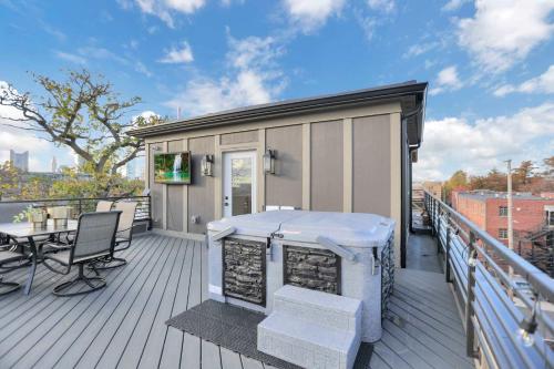 a large deck with a table and chairs on it at The Golden Hour - Luxury and Rooftop Hot Tub in Columbus