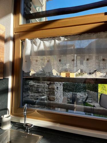 a kitchen window with a view of a stone wall at Chalet Letizia Mountain and Relax - Your Mountain Holiday in Premana