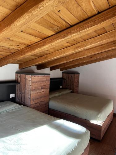 two beds in a room with wooden ceilings at Chalet Letizia Mountain and Relax - Your Mountain Holiday in Premana