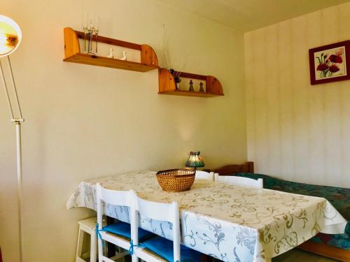 une salle à manger avec une table, des chaises et un panier dans l'établissement Appartement rénové avec balcon exposé plein sud, proche commerces et parking gratuit - FR-1-515-21, à Villard-de-Lans