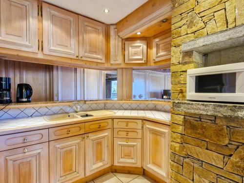- une cuisine avec des placards en bois et un mur en pierre dans l'établissement Appartement spacieux 4 étoiles, 4 pièces, sauna, au centre de Flaine Forêt, proche des pistes et commerces - FR-1-425-118, à Flaine
