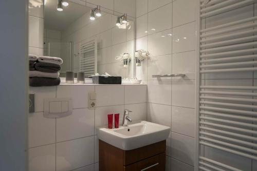 a white bathroom with a sink and a mirror at Gästehaus Orion - Wohnung 9 in Spiekeroog