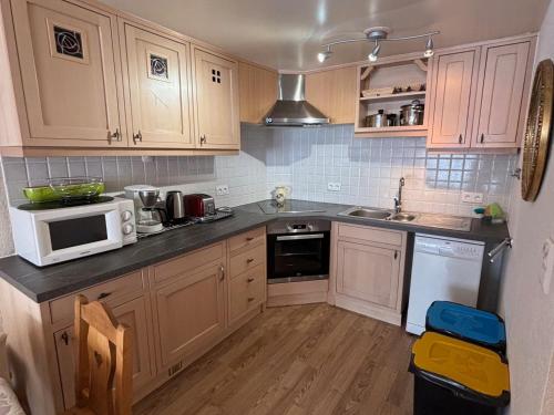 - une cuisine avec des placards en bois et un four micro-ondes blanc dans l'établissement Charmant 3 pièces avec terrasse exposée Sud, parking et tout équipé à La Chapelle-d'Abondance - FR-1-692-16, à La Chapelle-dʼAbondance