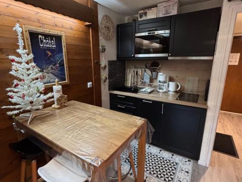 - une cuisine avec une table et un arbre de Noël dans l'établissement Studio chaleureux proche pistes avec balcon sud, casier à skis, parking et équipements complets. - FR-1-692-61, à La Chapelle-dʼAbondance