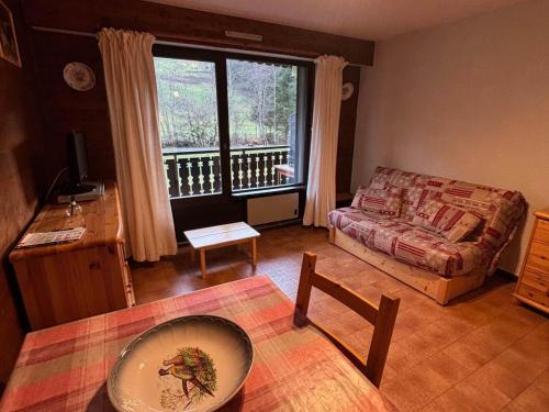 un salon avec un canapé et une grande fenêtre dans l'établissement Studio au pied des pistes avec balcon exposé Sud et parking – Animaux admis - FR-1-692-67, à La Chapelle-dʼAbondance