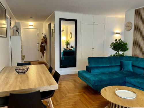 un salon avec un canapé bleu et une table dans l'établissement Appartement 5 personnes Léon Frot PARIS, à Paris
