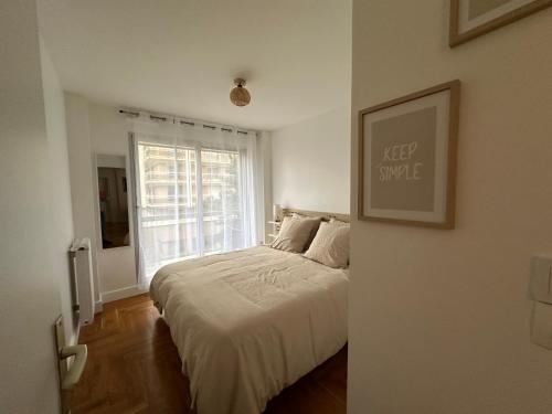 une chambre blanche avec un lit et une fenêtre dans l'établissement Appartement 5 personnes Léon Frot PARIS, à Paris